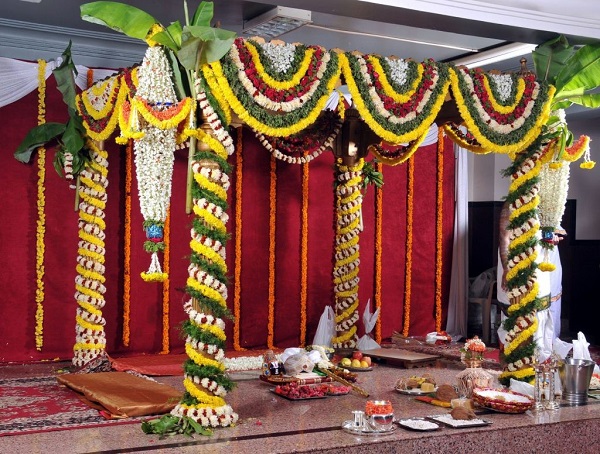 Wedding Hall mandap decorated with flowers and garlands in green yellow and white and red colours.